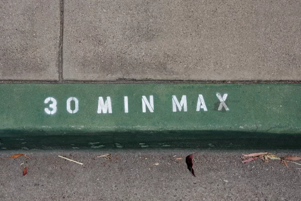 Close-up on green painted curb with '30 min max' in white.